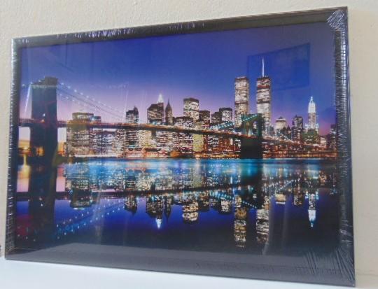 Oprawiony w ramę, nowy wydruk wielkoformatowy z nocnym widokiem na panoramę miasta z odbiciem w wodzie, zapakowany w folię ochronną.