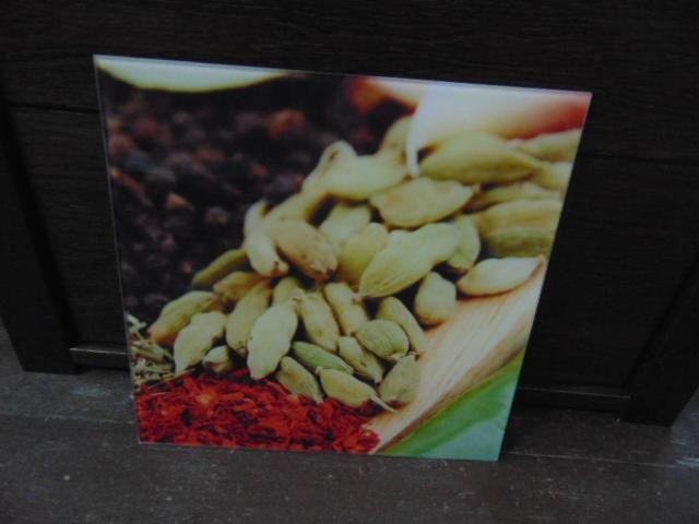 Druk wielkoformatowy: Kwadratowy wydruk z bliska przedstawiający przyprawy, kardamon, szafran i czarny pieprz, na tle ciemnego drewna.