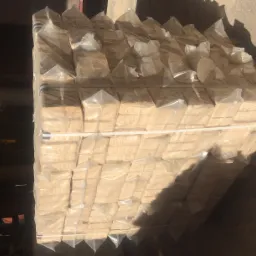 Paleta z kostkami opałowymi RUF owiniętymi w przezroczystą folię, zabezpieczona taśmami, w magazynie z betonową podłogą.