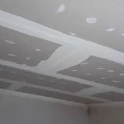 Sufit z płyt kartonowo-gipsowych połączonych szpachlą, widoczne łączenia i miejsca po wkrętach przed nałożeniem warstwy wykończeniowej.