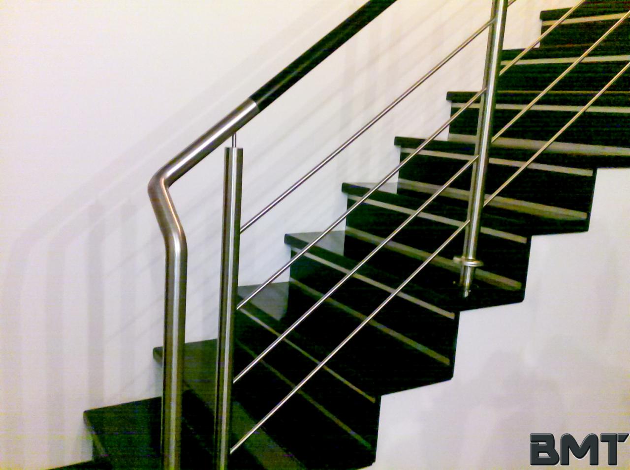 Nowoczesne schody z ciemnego kamienia z balustradą ze stali nierdzewnej. Minimalistyczny design i precyzyjne wykonanie detali.