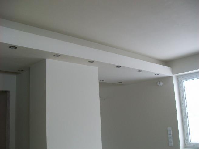 Białe wnętrze po remoncie: ściany, sufit z wbudowanym oświetleniem punktowym, okno. Minimalistyczny styl, gładkie powierzchnie, jasne barwy. Wykończenie wnętrz.