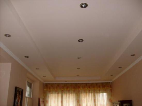 Jasny sufit z ozdobnymi listwami i punktowym oświetleniem, widok z dołu. Wykończenie wnętrza z dekoracyjnymi elementami.