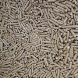 Jasne, brązowe pellety świerkowo-dębowe ułożone na metalowej siatce, widoczne delikatne ślady pyłu drzewnego.