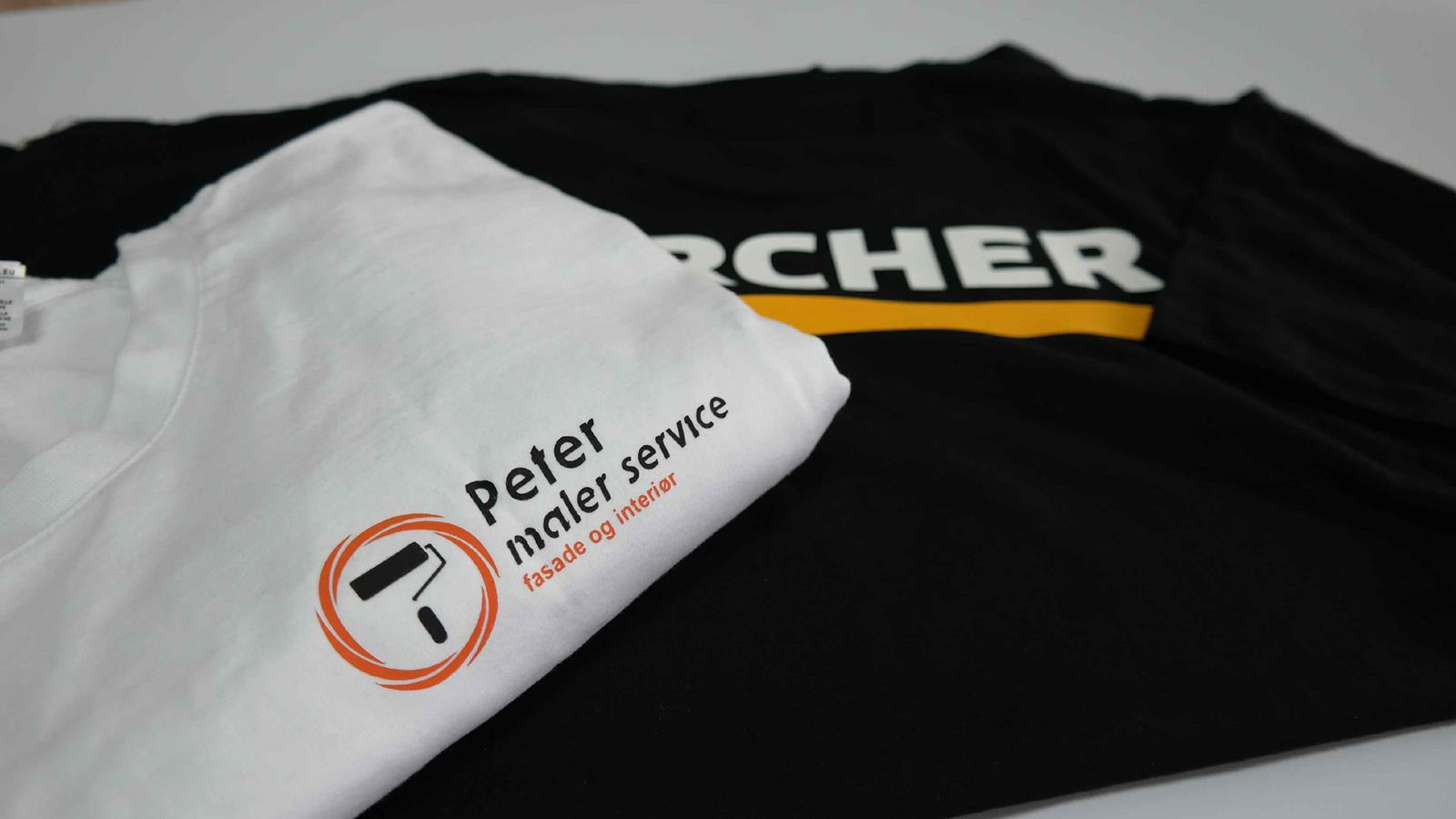 Dwa T-shirty: biały z nadrukowanym logo firmy malarskiej 'Peter maler service' z symbolem wałka i pędzla w pomarańczowym okręgu, oraz czarny z dużym białym napisem 'RCHER' i żółtym paskiem.