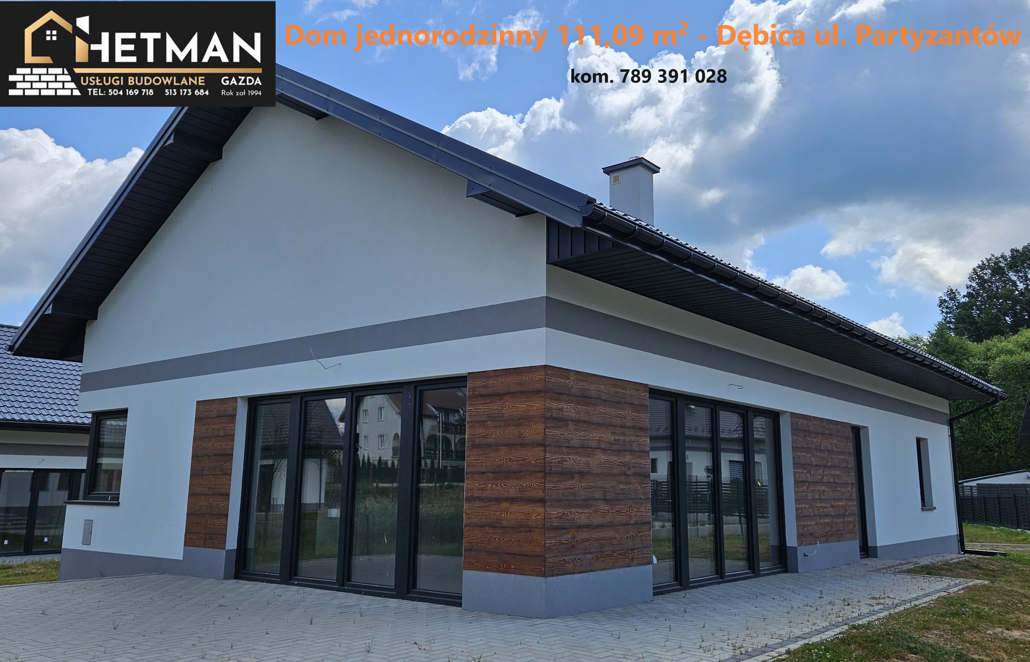 Nowoczesny parterowy dom jednorodzinny z elementami dekoracyjnymi imitującymi drewno na elewacji, widoczne duże okna tarasowe i szara listwa dekoracyjna pod dachem, na pierwszym planie wyłożony...