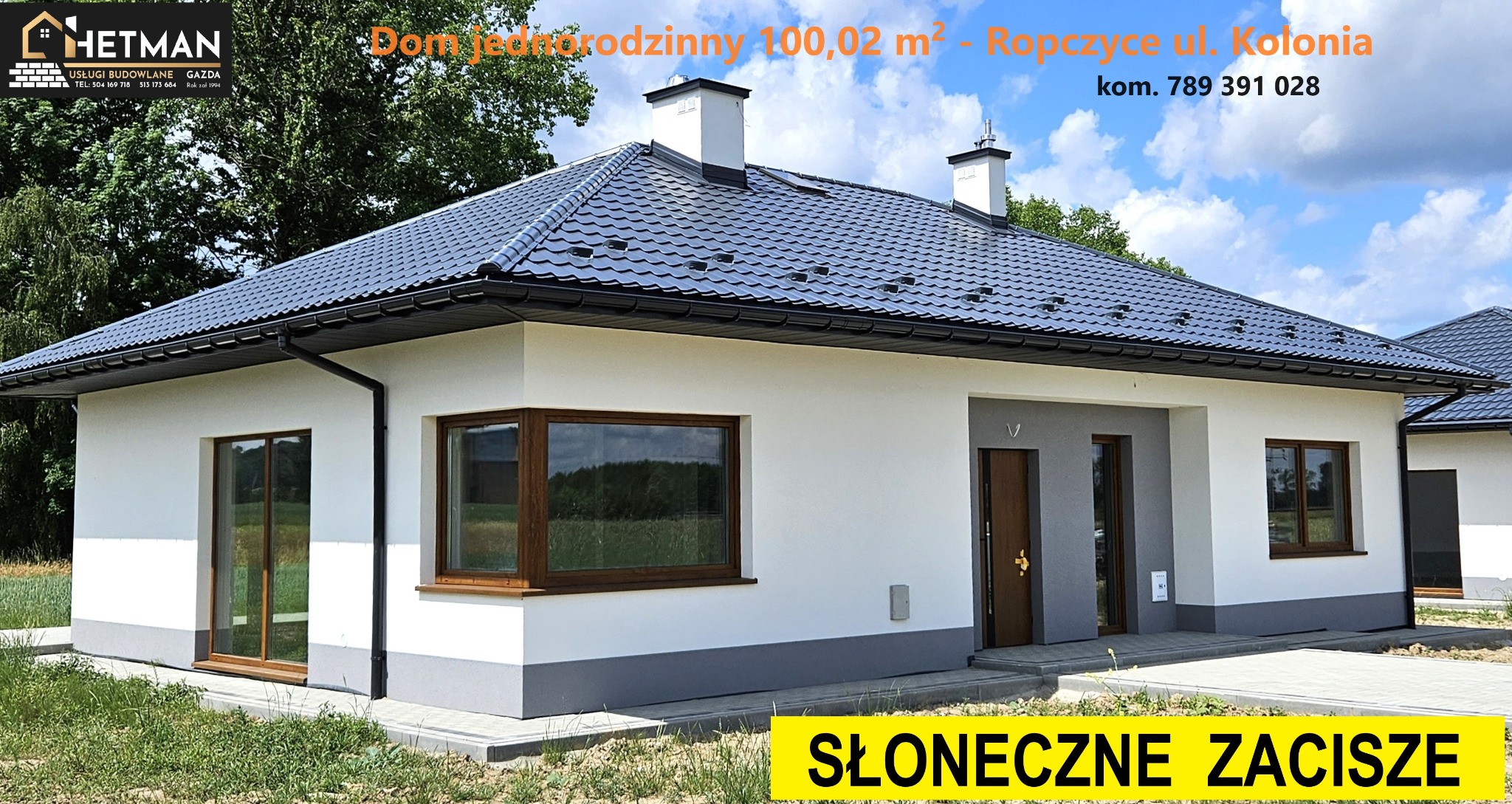 Nowoczesny, parterowy dom jednorodzinny z ciemną dachówką, białymi ścianami i szarym cokołem, widoczne okna z brązowymi ramami, dwa kominy i logo firmy budowlanej w rogu zdjęcia.