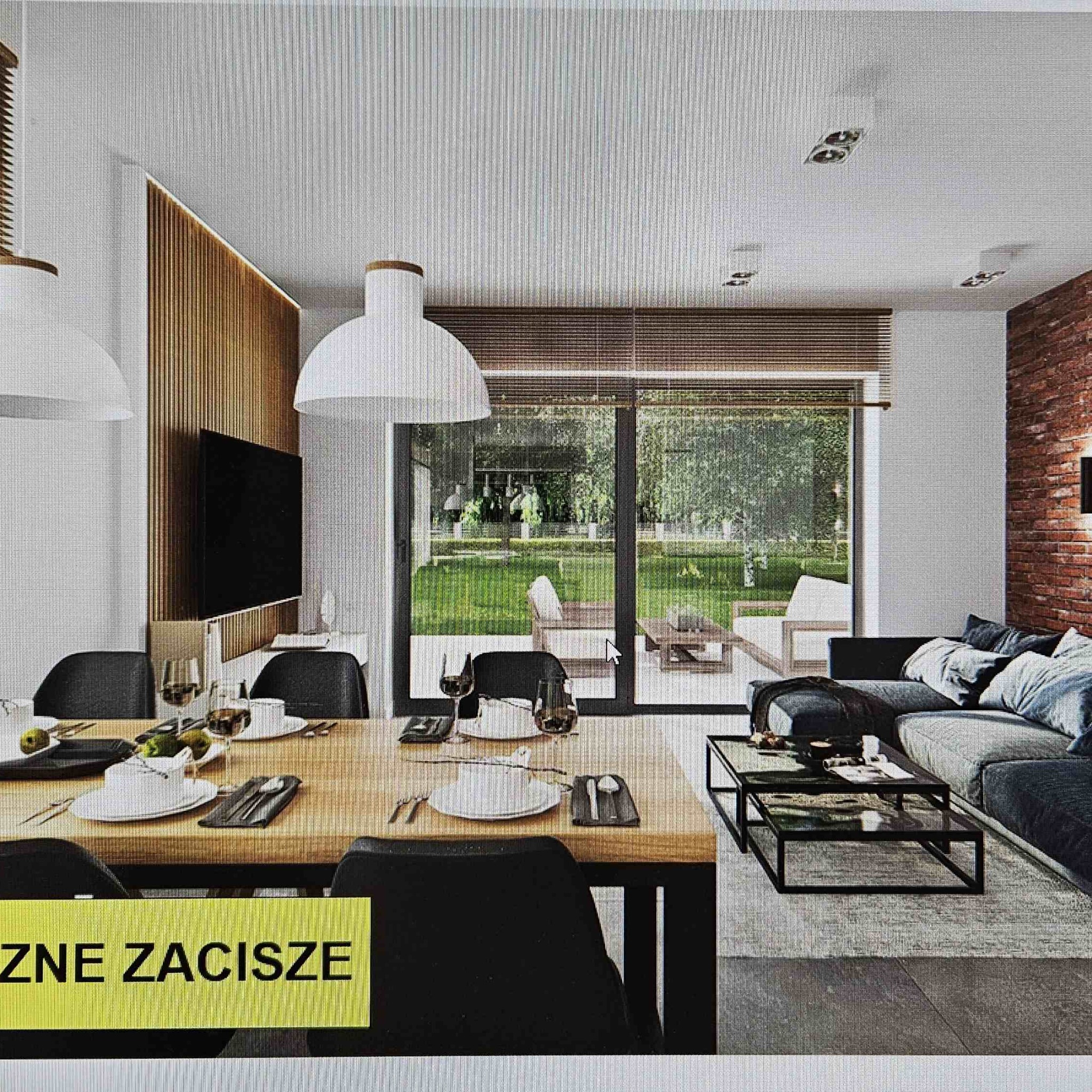 Jasne, przestronne wnętrze domu z dużym oknem na ogród, drewnianą ścianą z telewizorem i ceglaną ścianą, stół z nakryciem i sofa z poduszkami.