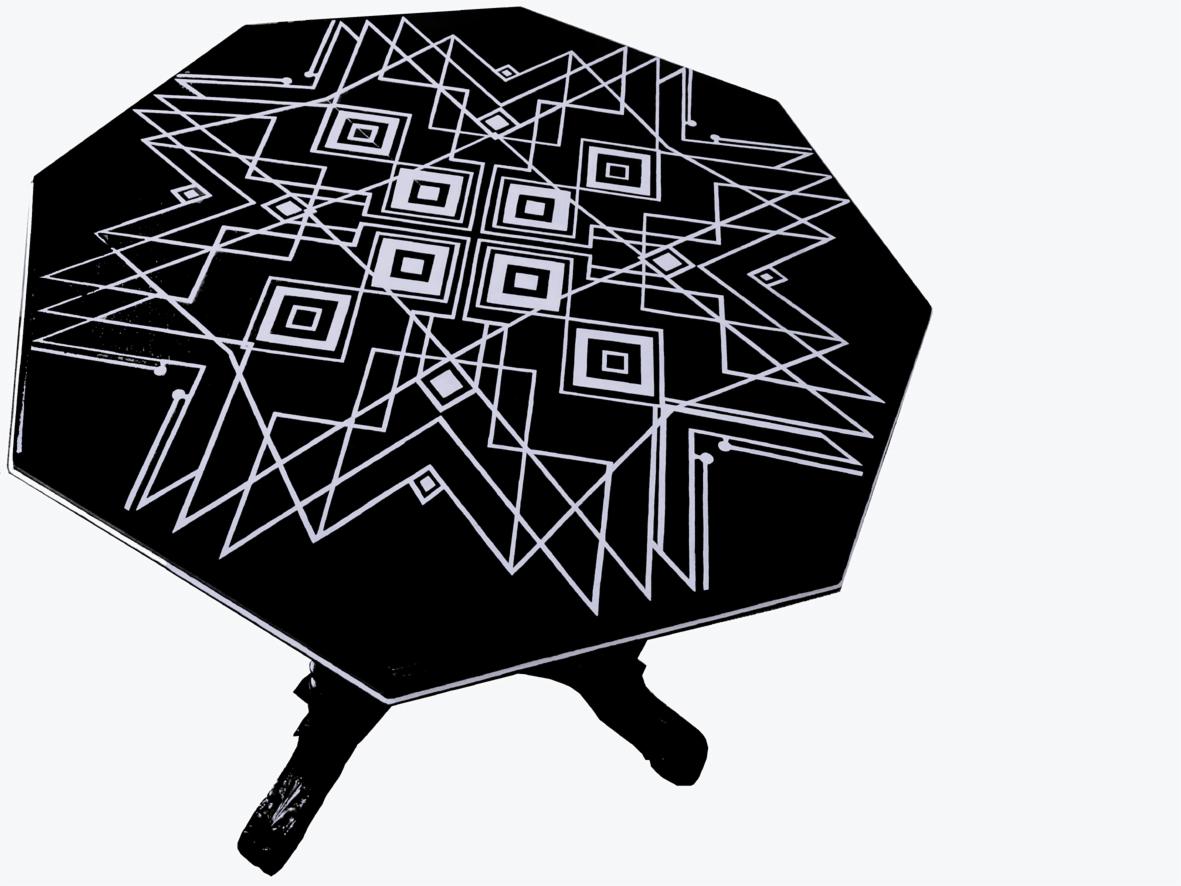 Czarny, ośmiokątny stolik z geometrycznym, białym wzorem w stylu art deco. Widoczne trzy nogi. Ujęcie z góry, na białym tle.