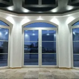 Wykończone wnętrze z marmurową posadzką i dużymi, łukowymi oknami z białymi ramami. Sufit z oknami i oświetleniem punktowym. Nowoczesny design.