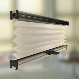 Beżowa żaluzja plisowana z czarną ramą, widoczna z boku na rozmytym tle wnętrza, pokazująca strukturę materiału i mechanizm składania.