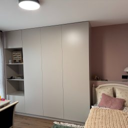 MG MEBLE MICHAŁ GRYT - Jasnoszara szafa wnękowa z otwartymi półkami w pokoju dziecięcym z łóżkiem i biurkiem.