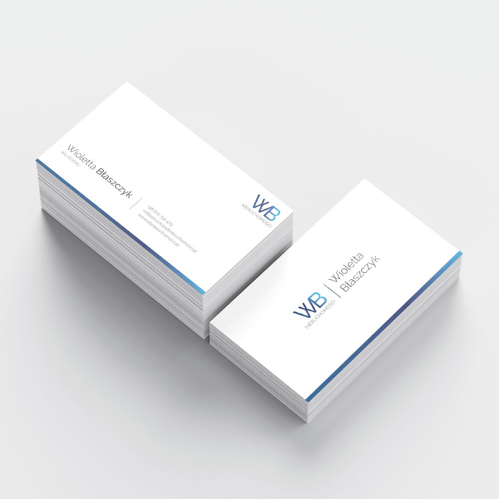 Dwie stosy wizytówek z gradientem koloru niebieskiego na krawędziach, logo 'WB Nieruchomości' i danymi kontaktowymi Wiolletty Błaszczyk, ułożone na jasnoszarym tle.