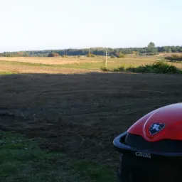 Przygotowany teren pod budowę lub nasadzenia, widoczny z perspektywy czerwonego traktora Antonio Carraro, w tle pola i linia energetyczna.