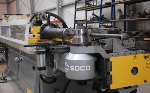 Automatyczna giętarka trzpieniowa SB-63Auto marki SOCO do rur i profili stalowych w hali produkcyjnej, widoczne elementy mocujące i gięta rura.