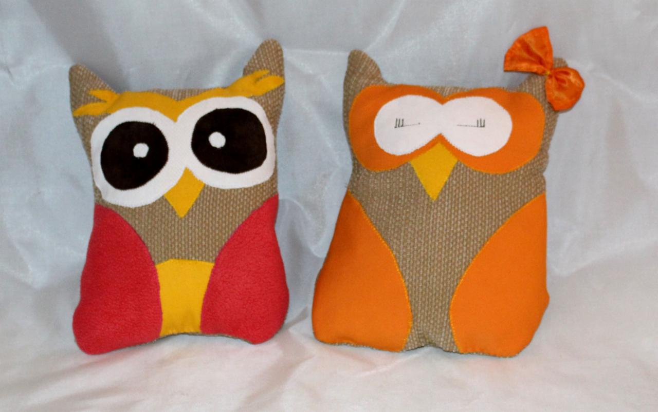 Dwa dekoracyjne, ręcznie robione pluszaki w kształcie sów, jedna z kokardką, na białym tle. Idealne jako element wystroju wnętrz lub prezent.