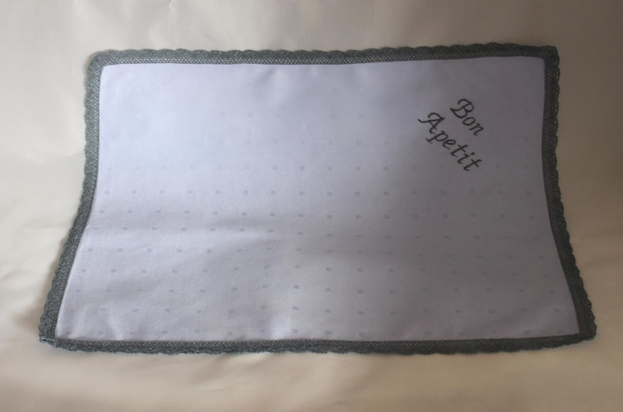 Elegancka serweta z napisem 'Bon Apetit' i ozdobnym, szarym obramowaniem, idealna do koszy prezentowych z żywnością.