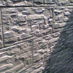 Szara ściana z dekoracyjnej, imitującej kamień okładziny elewacyjnej, ułożonej w regularny wzór z widocznymi fugami. Teksturowana powierzchnia, ukośny kadr.