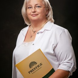 PRESTIGE Nieruchomości Iwona Fryszkowska - Profesjonalny portret kobiety w okularach, trzymającej folder 'Prestige Nieruchomości' na ciemnym tle. Biała koszula, biżuteria. Uśmiech.