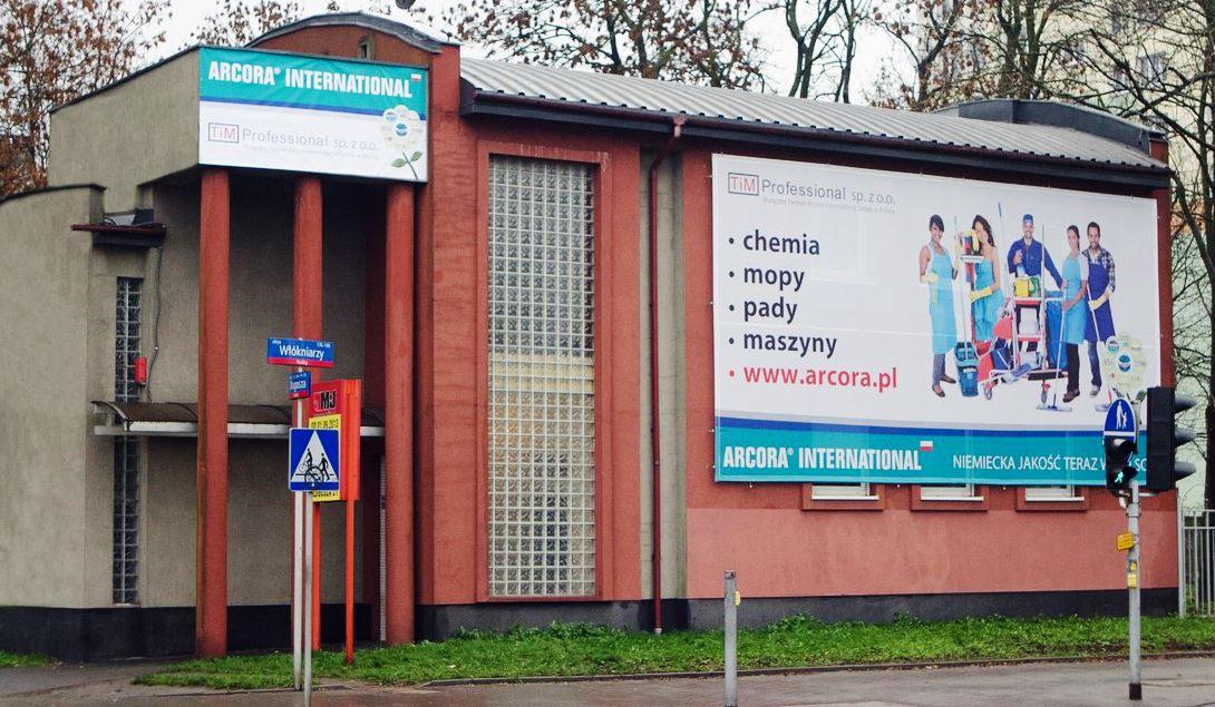 Budynek firmy ARCORA SHOP w Łodzi z dużym banerem reklamowym prezentującym chemię, mopy, pady i maszyny do sprzątania.