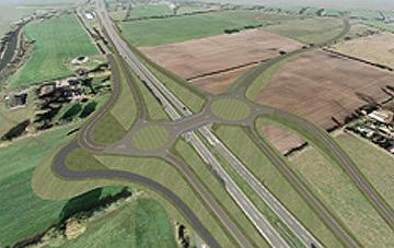 Widok z lotu ptaka na nowo wybudowany węzeł drogowy z rondami i estetycznymi nasadzeniami zieleni, otoczony polami uprawnymi.