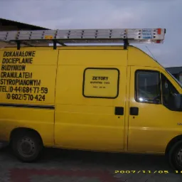 Żółty bus z drabiną na dachu i reklamą ocieplania budynków granulatem styropianowym. Widoczne worki z materiałem izolacyjnym. Data zdjęcia: 2007/11/05.