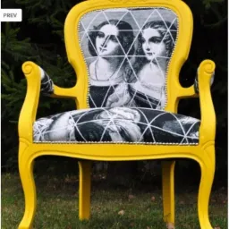 Żółty fotel z tapicerką w czarno-białe portrety kobiet, ozdobiony białymi liniami tworzącymi geometryczny wzór, stojący na trawie.