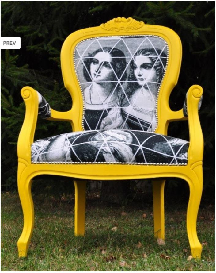 Żółty fotel z tapicerką w czarno-białe portrety kobiet, ozdobiony białymi liniami tworzącymi geometryczny wzór, stojący na trawie.