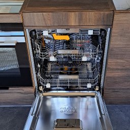 Firma WKTM - Otwarta zintegrowana z zabudową kuchenną zmywarka Whirlpool z widocznymi koszami i napisem MAXI SPACE na dnie.