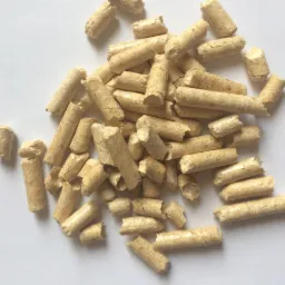 Jasne, drobne pellety drzewne ułożone w stos na białym tle, widoczne drobne pęknięcia i nierówności w strukturze.