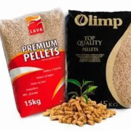 Dwa worki pelletu: czerwony z napisem LAVA Premium Pellets 15kg i czarny Olimp Top Quality Pellets, z przodu rozsypany pellet i mała roślina.