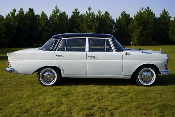 Elegancki, biały zabytkowy Mercedes z czarnym dachem na trawniku, idealny na wyjątkowe okazje i stylowe przewozy osób.