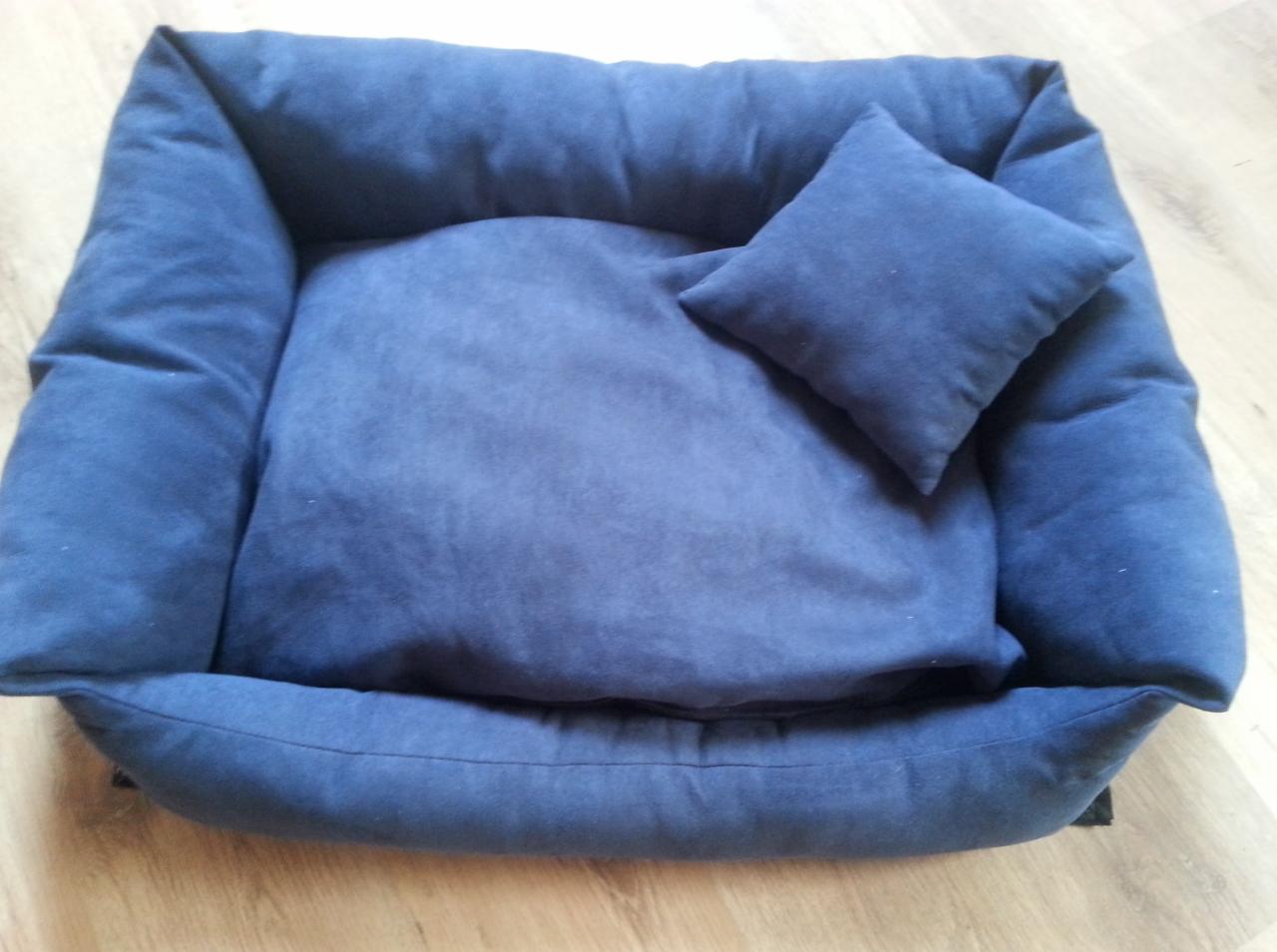 Granatowe, pluszowe legowisko dla psa z poduszką, widoczne z góry na drewnianej podłodze. Minimalistyczny design, miękkie materiały, idealne dla małego psa.