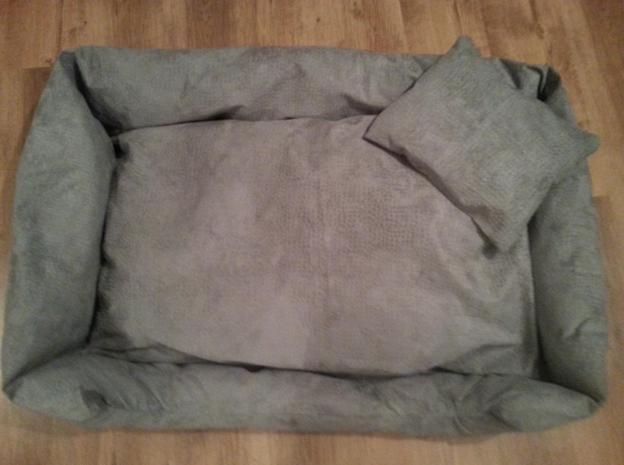 Gotowe, szare legowisko ortopedyczne dla psa z poduszką, wykonane z miękkiego, pluszowego materiału, leżące na drewnianej podłodze.