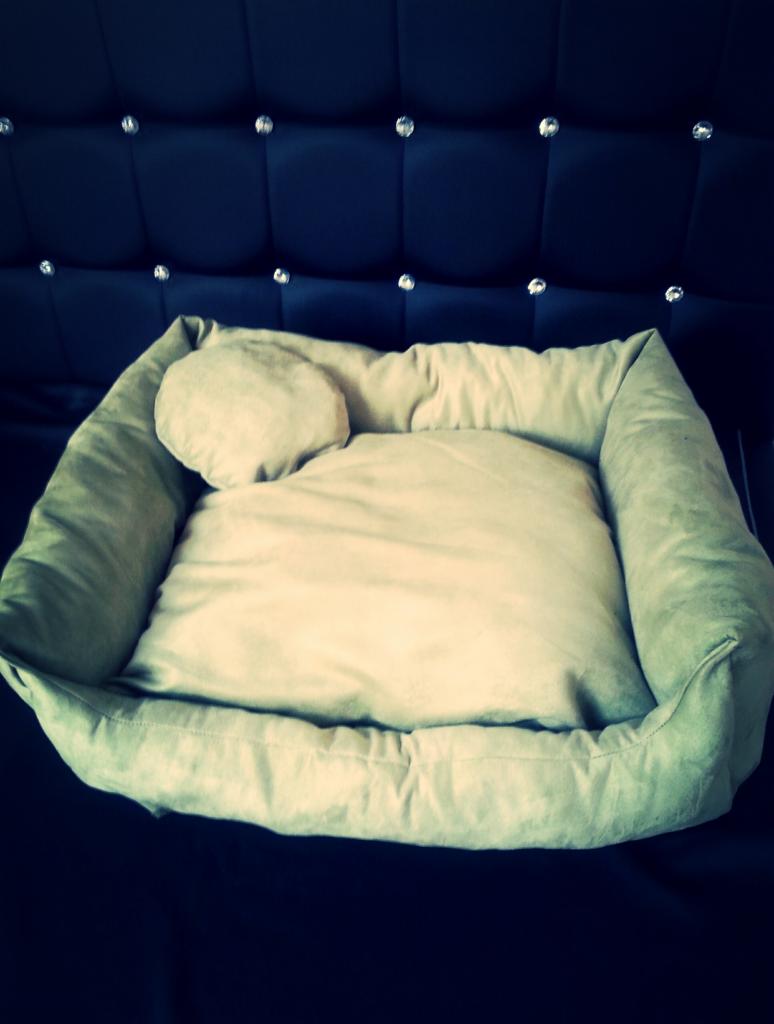 Beżowe legowisko dla psa z poduszką na tle pikowanego zagłówka z kryształkami, prezentujące estetyczne wykonanie i dbałość o detale.