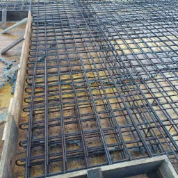 Siatka zbrojeniowa ułożona w drewnianym szalunku, widoczne plastikowe dystanse, przygotowana do zalania betonem.