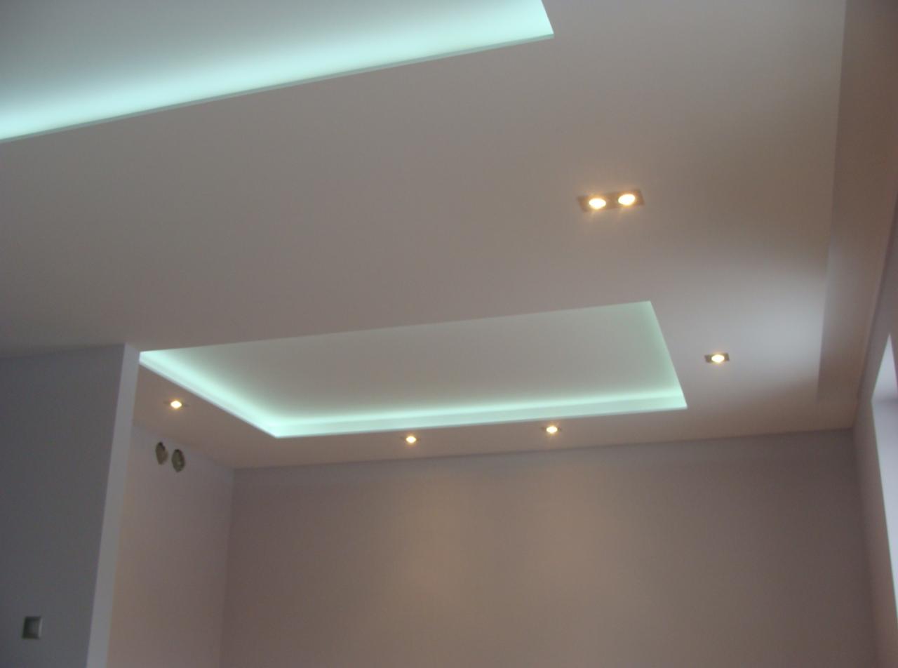 Nowoczesny sufit podwieszany z oświetleniem LED w jasnym pomieszczeniu. Widoczne detale wykończenia i punktowe źródła światła.