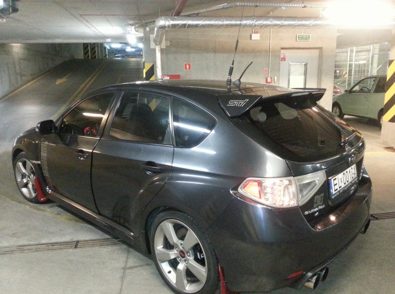 Szary Subaru Impreza STI w garażu podziemnym w Piasecznie. Widoczny spojler, felgi i czerwone chlapacze. Detailing auta po tuningu.