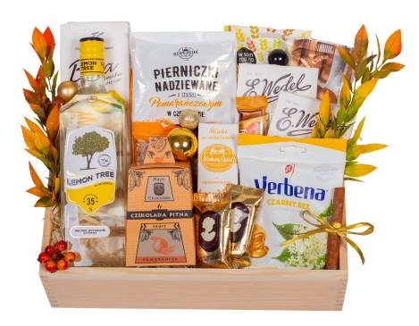 Drewniana skrzynka wypełniona różnorodnymi produktami spożywczymi, w tym butelką Lemon Tree, pierniczkami nadziewanymi, czekoladą pitną Maja, herbatą Verbena, słodyczami Wedel, oraz dekoracjami...