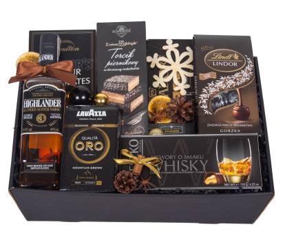 Elegancki, czarny kosz wypełniony alkoholem, kawą Lavazza Oro, czekoladami Lindt Lindor i torcikiem piernikowym, udekorowany suszonymi pomarańczami i szyszkami.