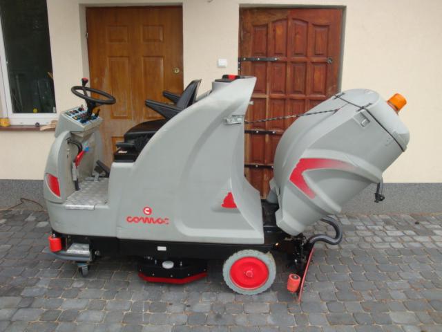 Szorowarka Comac Ultra 85B na kostce brukowej przed drewnianymi drzwiami, widok z boku.