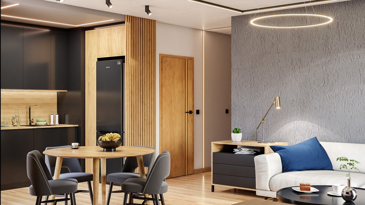 Wnętrze salonu z aneksem kuchennym: okrągły stół z szarymi krzesłami, czarna zabudowa kuchenna z drewnianymi akcentami, szara ściana z lampką, biała sofa z niebieską poduszką i okrągły stolik kawowy.