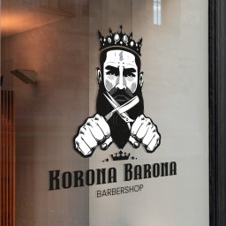Michał Drzewski - Grafika na szkle: brodaty mężczyzna w koronie trzyma skrzyżowane brzytwy, poniżej napis 'Korona Barona Barbershop'. Widok z zewnątrz, fragment okna i wnętrza.
