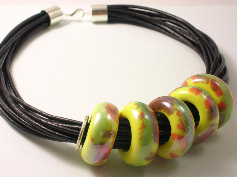 Ręcznie robiony naszyjnik z czarnych rzemieni i kolorowych, ceramicznych koralików w odcieniach zieleni, żółci i czerwieni. Srebrne zapięcie.