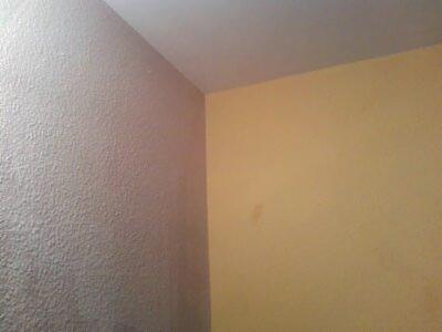 Fragment pokoju: ściana z fakturą w odcieniach szarości łączy się ze ścianą pomalowaną na żółto. Widoczny narożnik i fragment sufitu. Tekstura ściany szarej jest wyraźnie widoczna.