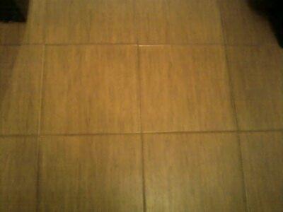 Ułożona podłoga z płytek ceramicznych w odcieniach brązu, widok z góry, fuga w kolorze zbliżonym do płytek. Lekki połysk, ciepłe oświetlenie.