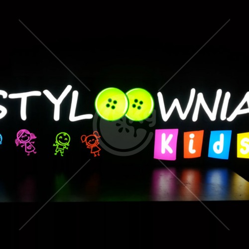Podświetlany szyld reklamowy 'Styloownia Kids' z elementami graficznymi w stylu dziecięcym: dwa duże zielone guziki imitujące oczy i kolorowe postacie dzieci. Szyld umieszczony na czarnym tle...