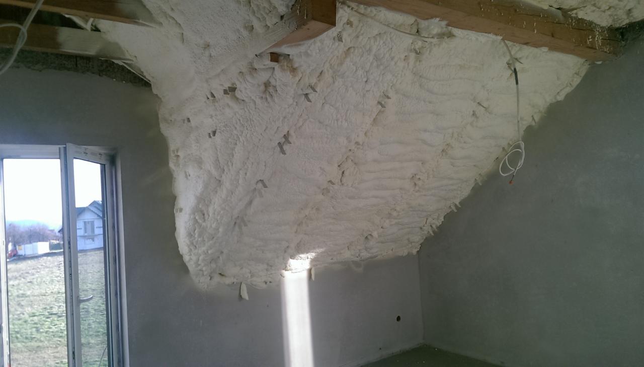 Poddasze po ociepleniu pianką PUR, widoczne drewniane belki stropowe, okno, oraz fragment instalacji elektrycznej.