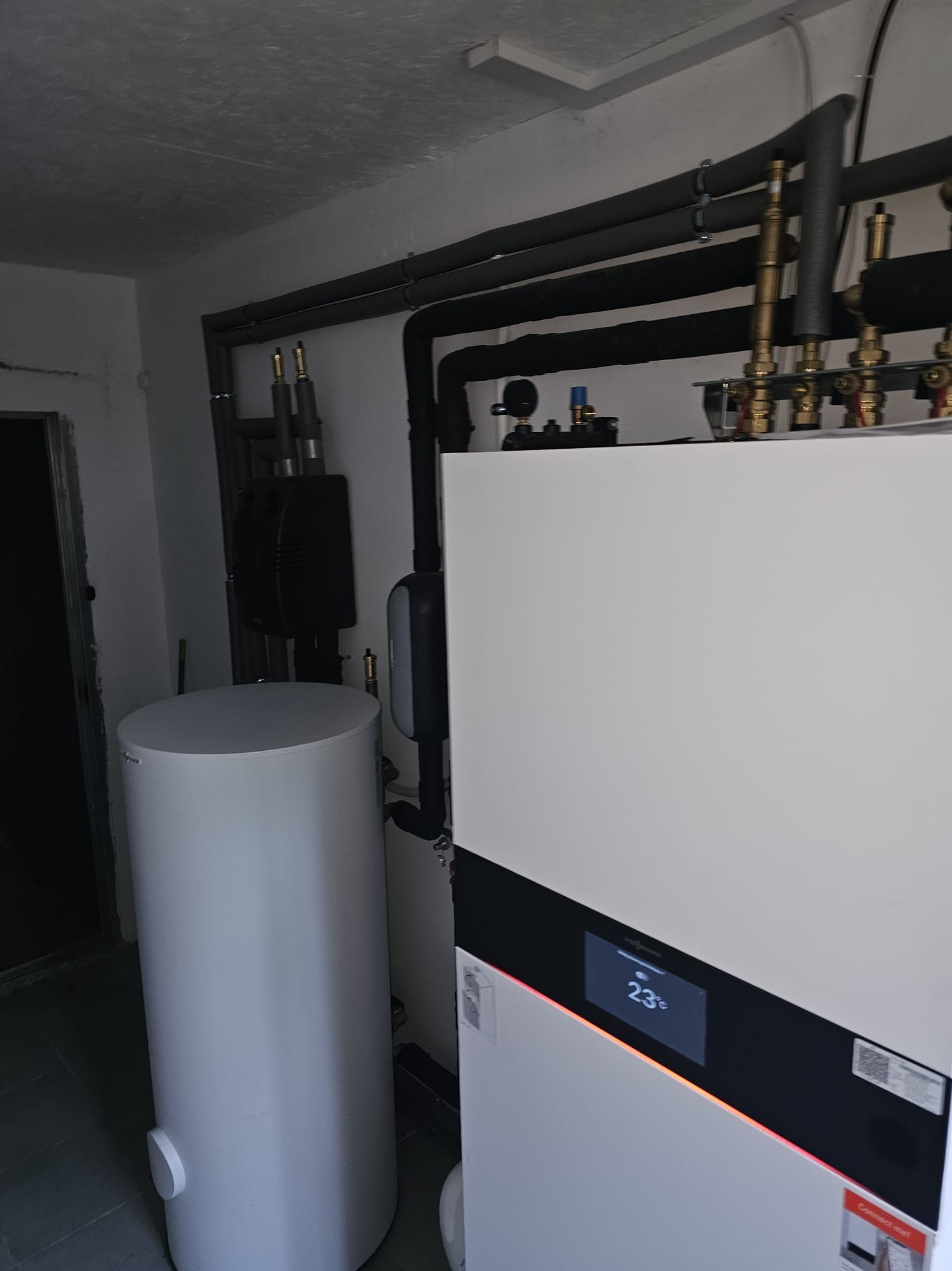 Kompaktowa instalacja grzewcza Viessmann: kocioł gazowy i pompa ciepła monoblok, rury w izolacji, zbiornik na wodę. Nowoczesne rozwiązanie w kotłowni.