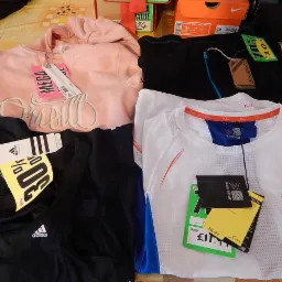 Różnorodna odzież sportowa: różowa bluza O'Neill, czarne legginsy Adidas z metką 30% off, biała koszulka Karrimor Run z metką £11.11 i czarna bluza Campri z metką 70% off.